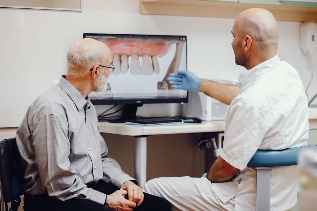 Il dentista spiega i rischi e le controindicazione degli impianti dentali a un paziente